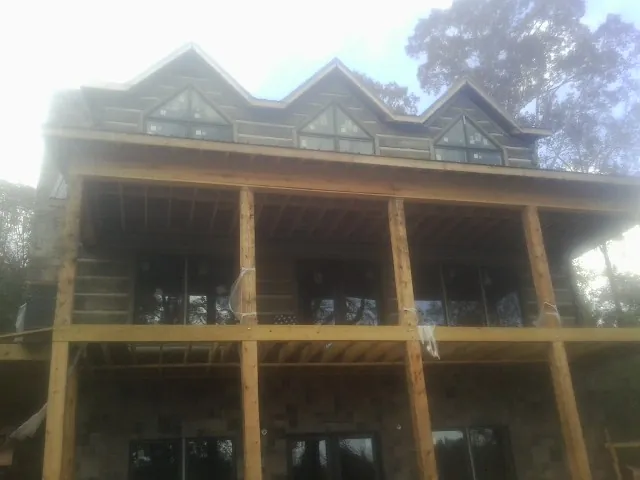 Dormers and porch framing on a large log home under construction — Roof Coating work by our crew in Granite Falls
