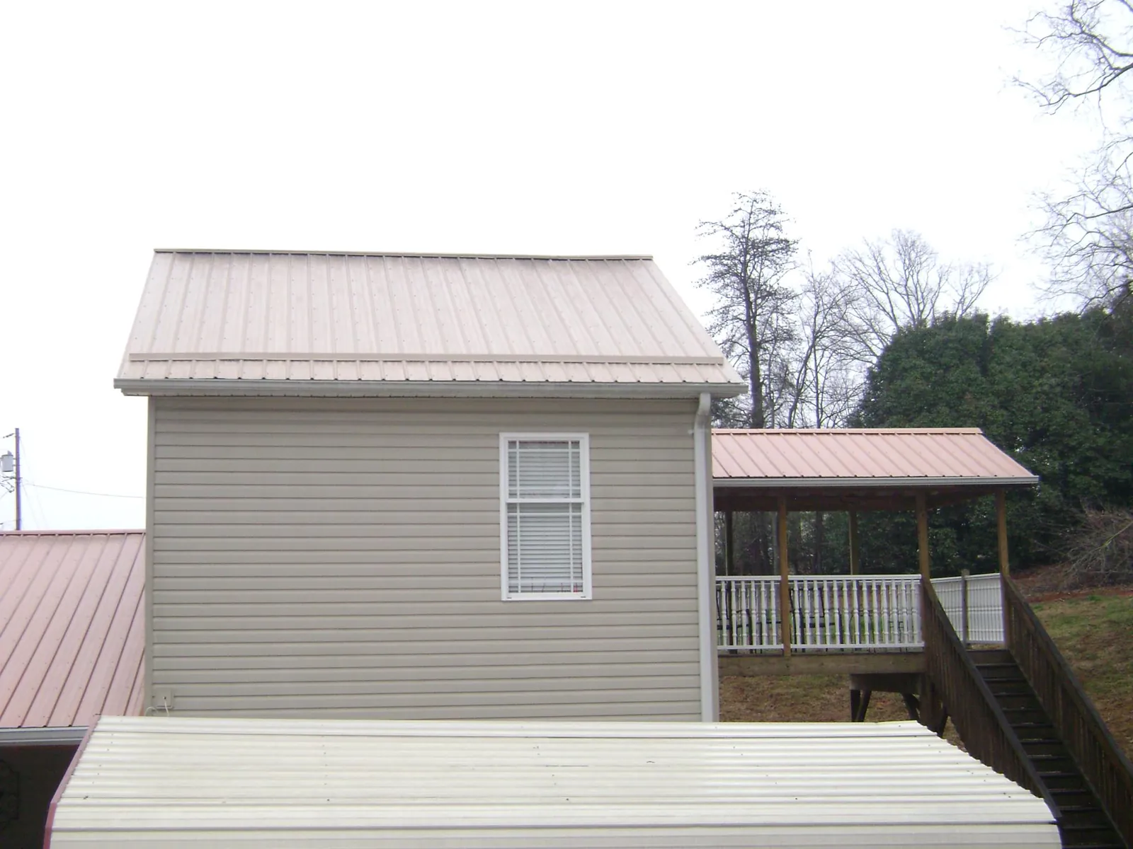 Tan metal roofs on a two story addition and attached porch, from a Roof Replacement job in Granite Falls